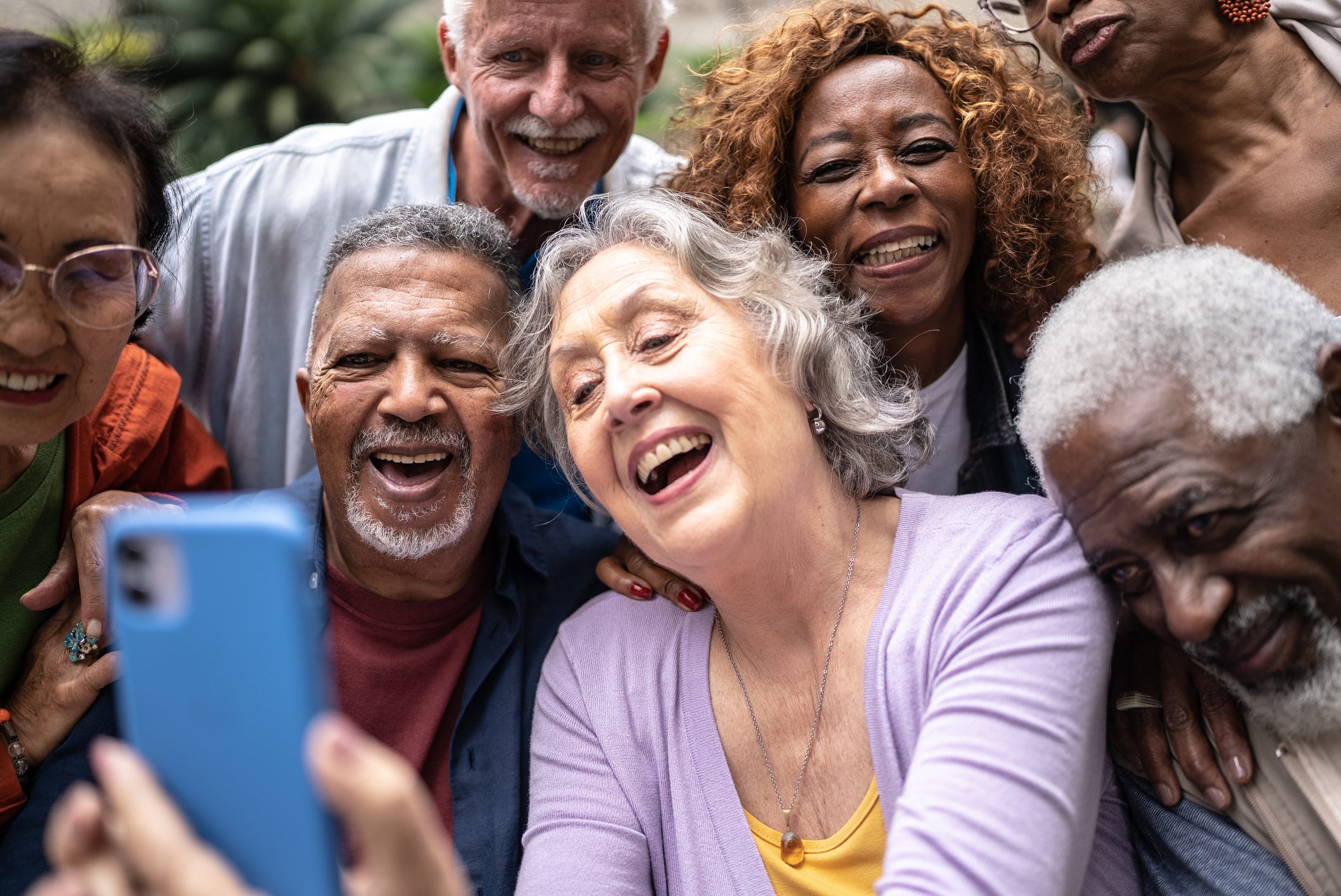 Senior friends taking a selfie or filming using mobile phone outdoors